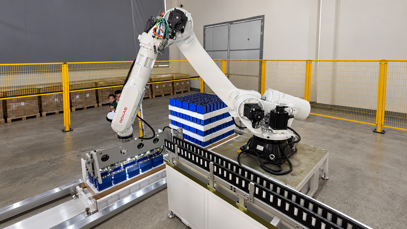Cánh tay robot công nghiệp ROKAE bên cạnh các khay cell pin trong khu vực xưởng.